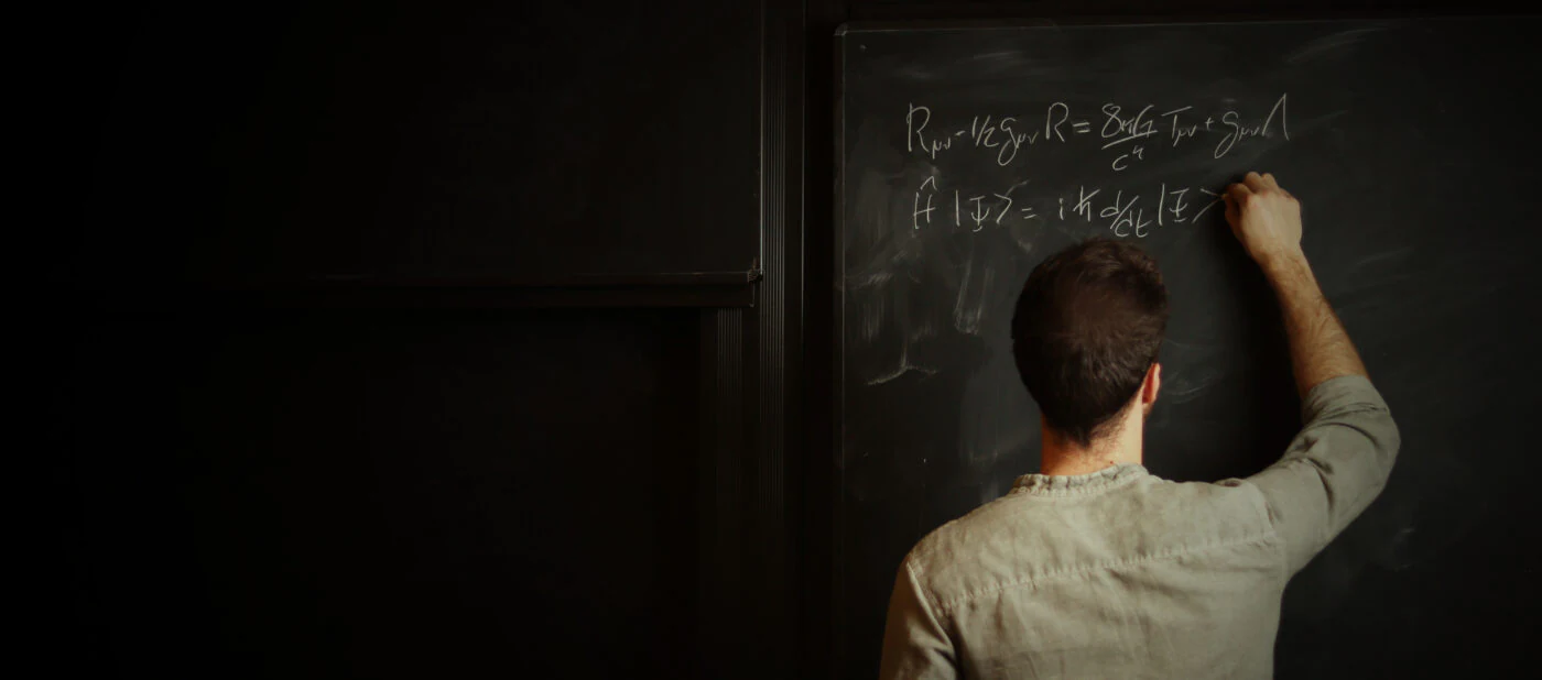 Guilherme Franzmann writing equations on a blackboard