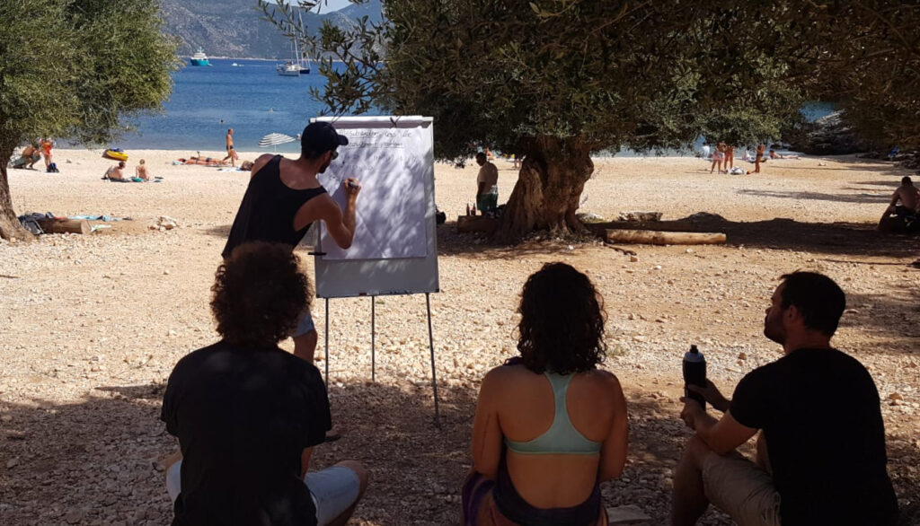 Guilherme Franzmann lecturing beside a blackboard at the Kefalonia Foundations Workshop